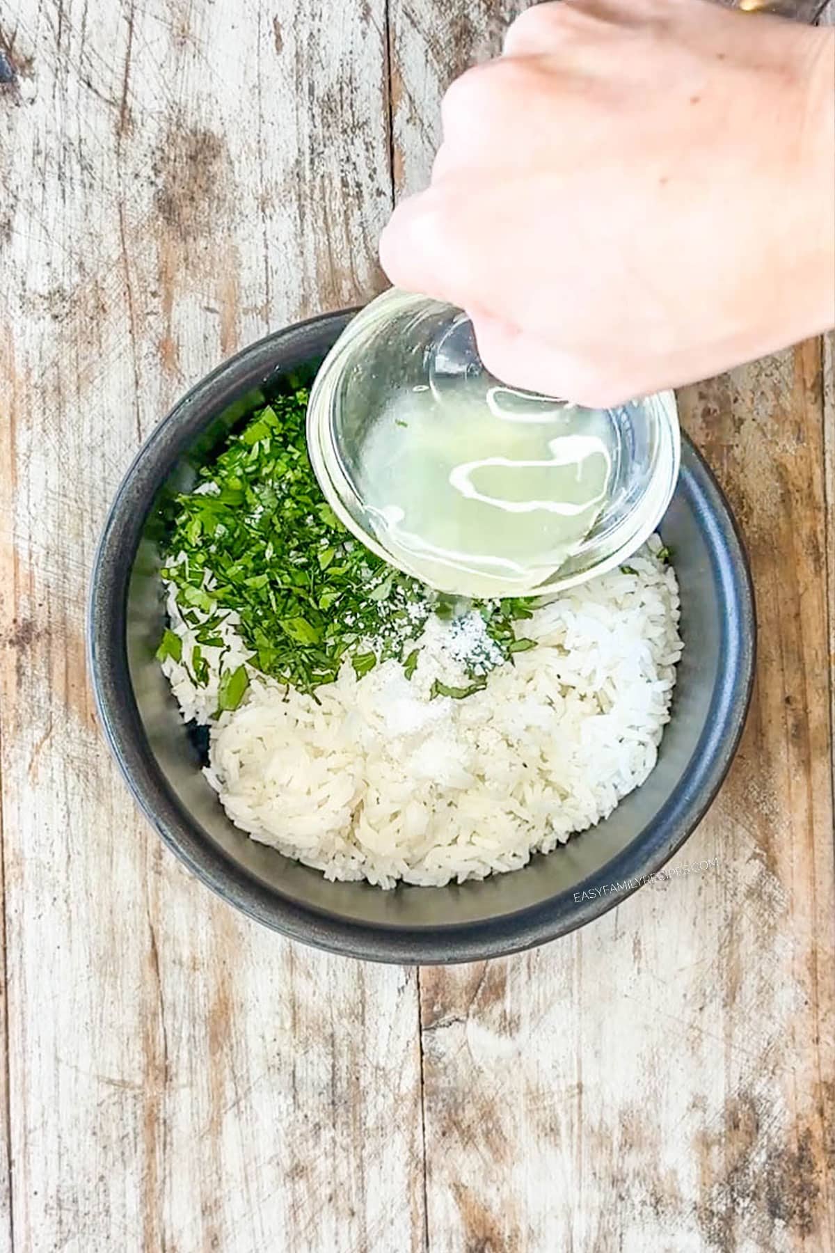 bowl with cooked rice, herbs and lemon juice pouring in