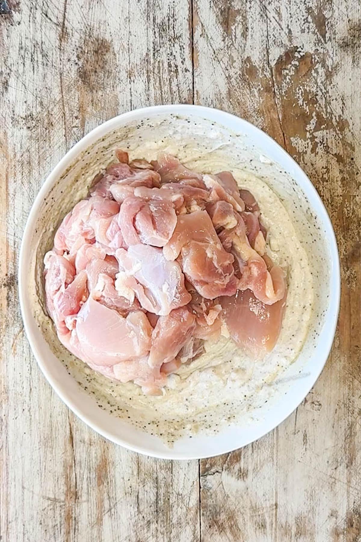 chopped chicken thighs in bowl with marinade