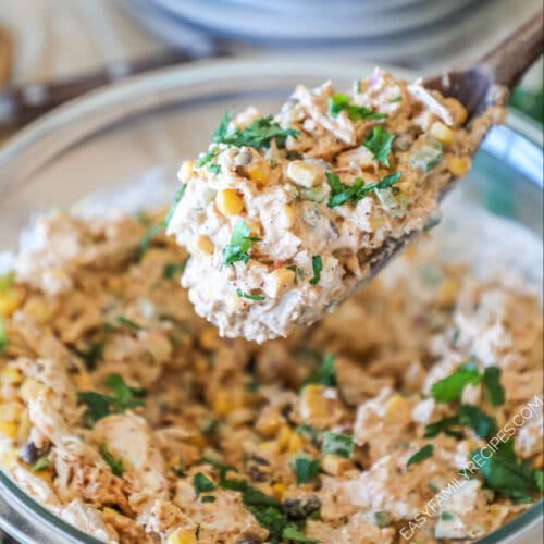 Mexican Chicken Salad in a glass bowl, with a wooden spoon lifting chicken salad out of the bowl
