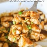 Oven baked orange chicken scoop up from the baking dish on a spatula.