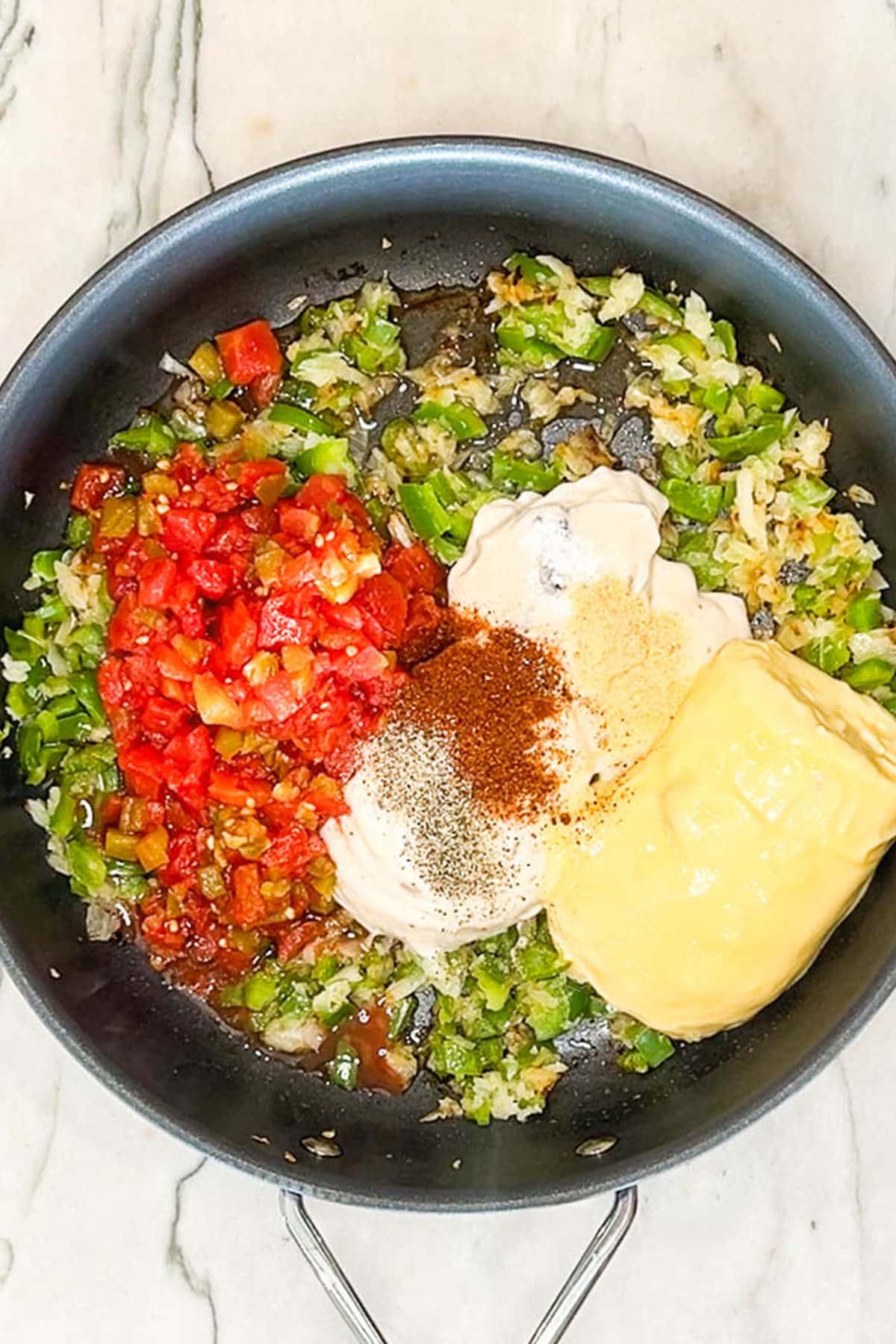Onion, green bell pepper, Rotel, condensed soups, and spices in a skillet.