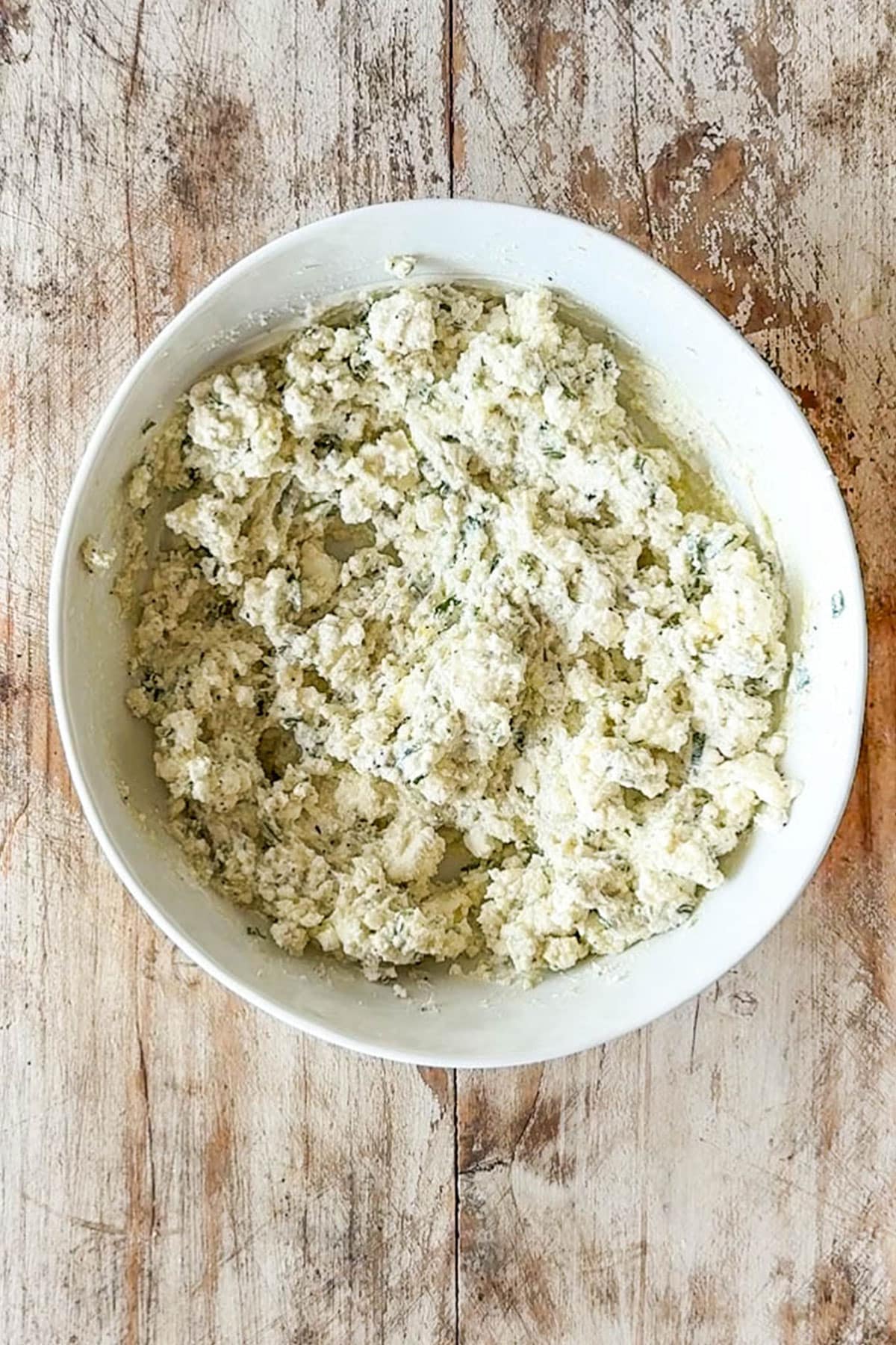 Mixture of feta, olive oil, lemon and seasonings in a white bowl