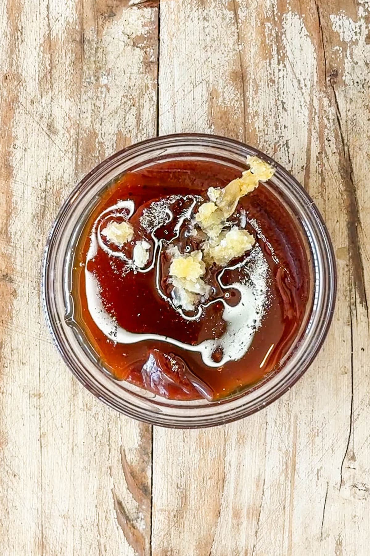 Barbecue sauce, honey, and garlic in a small jar.