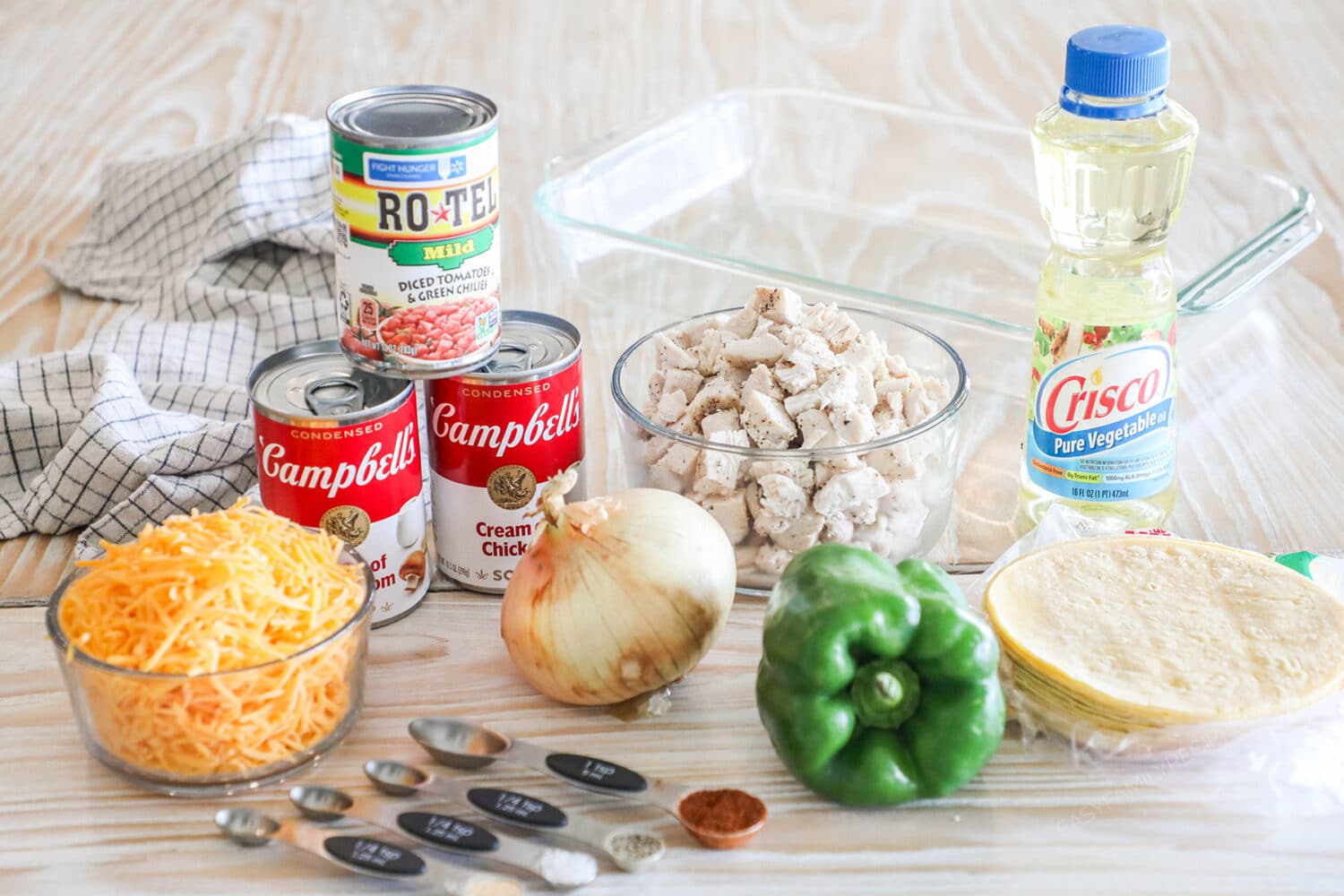 Ingredients needed to make a king ranch chicken casserole on a wooden background.