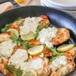Lemon Feta Chicken in a large skillet, topped with creamy feta mixture, lemon slices and parsley