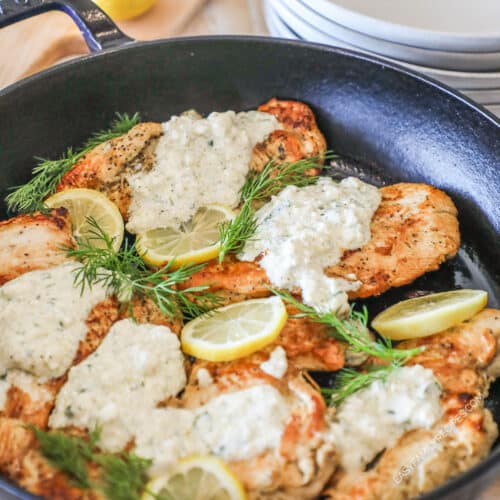 Lemon Feta Chicken in a large skillet, topped with creamy feta mixture, lemon slices and parsley