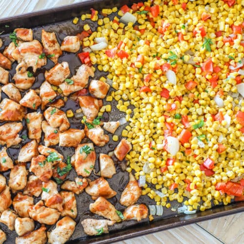 Overhead shot of finished sheet pan BBQ chicken bites and buttered corn on the sheet pan.