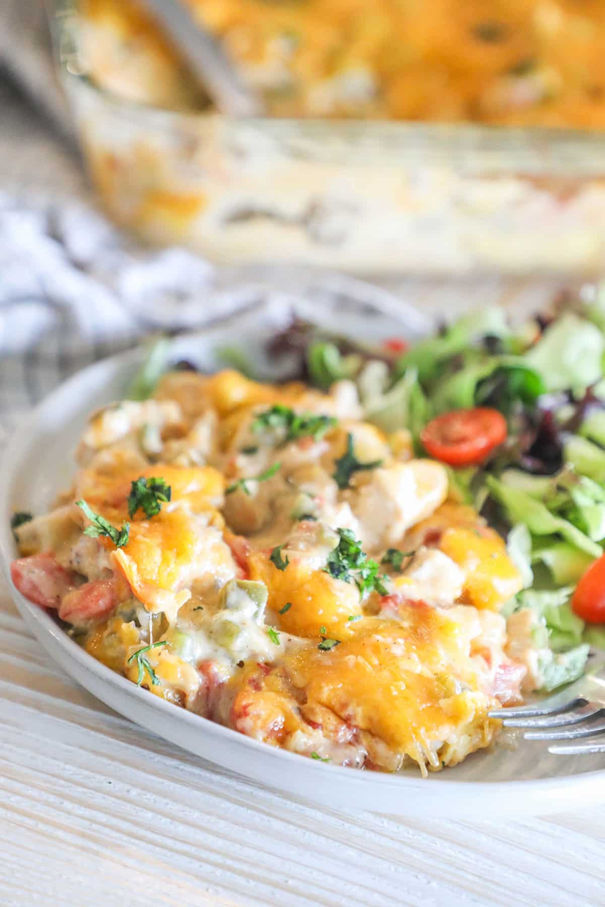 Portion of king ranch chicken casserole on a plate with a side salad.