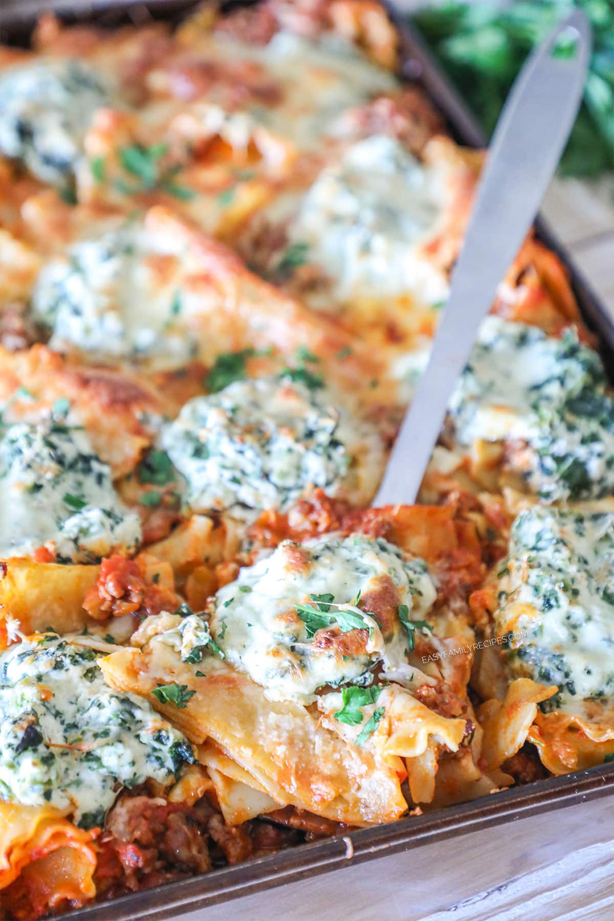Sheet Pan Lasagna lifted out of pan by metal spatula