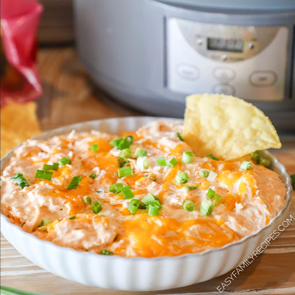 Crockpot Buffalo Chicken Dip in slow cooker topped with cheddar and green onions