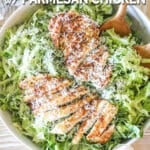 crispy parmesan chicken breasts sliced and placed over green goddess salad in a large white bowl with two wooden spoons- on a wooden background