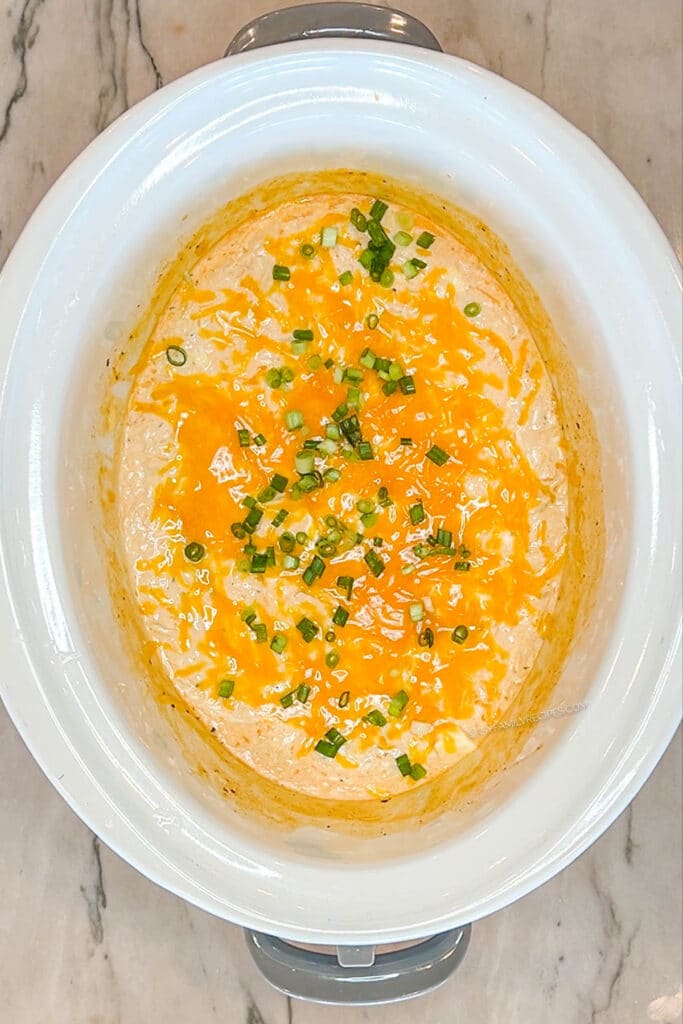 finished buffalo chicken dip crockpot topped with green onions.