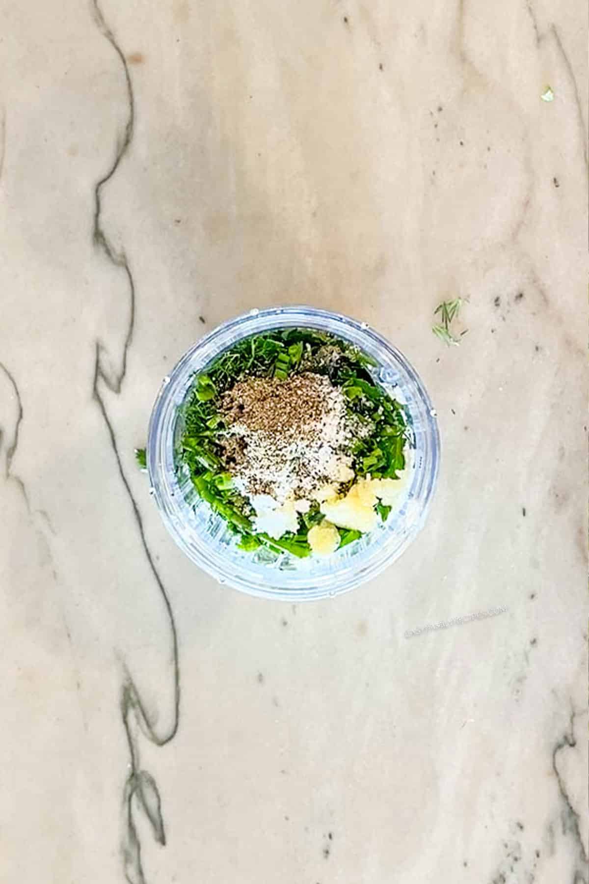 view looking into a cup of the ingredients for green goddess dressing before being blended together