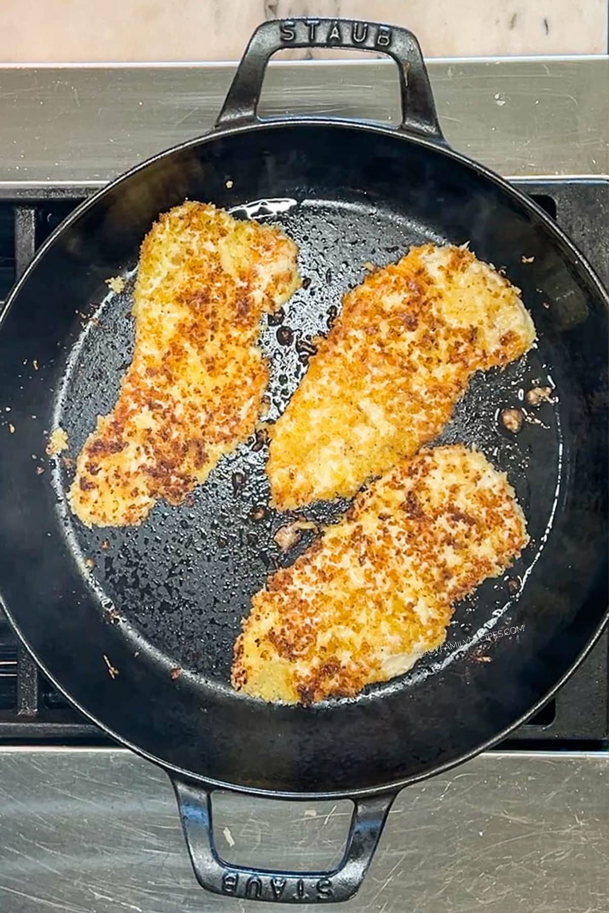parmesan and panko crusted chicken breasts in a skillet after being pan fried