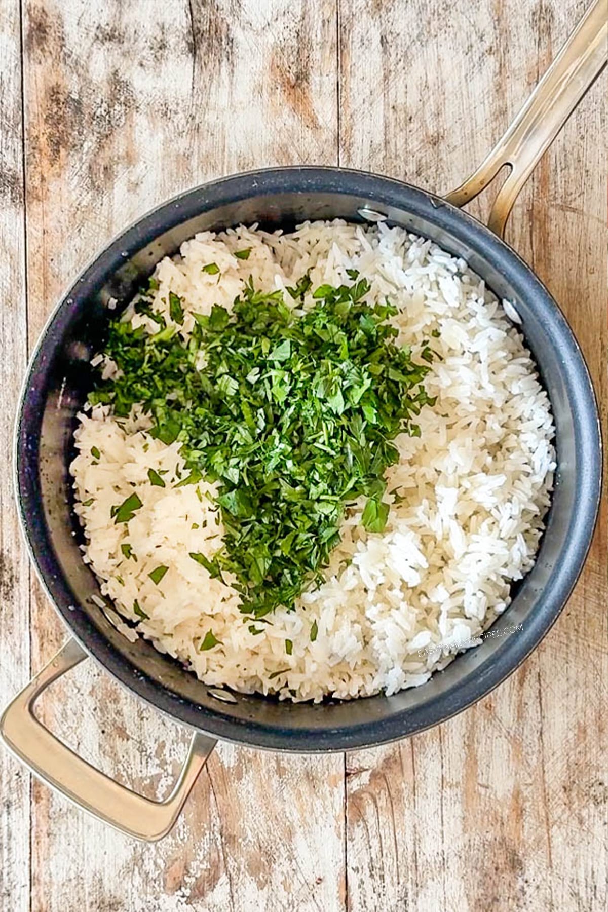 Overhead shot of rice with lots of chopped parsley on top in a saucepan.