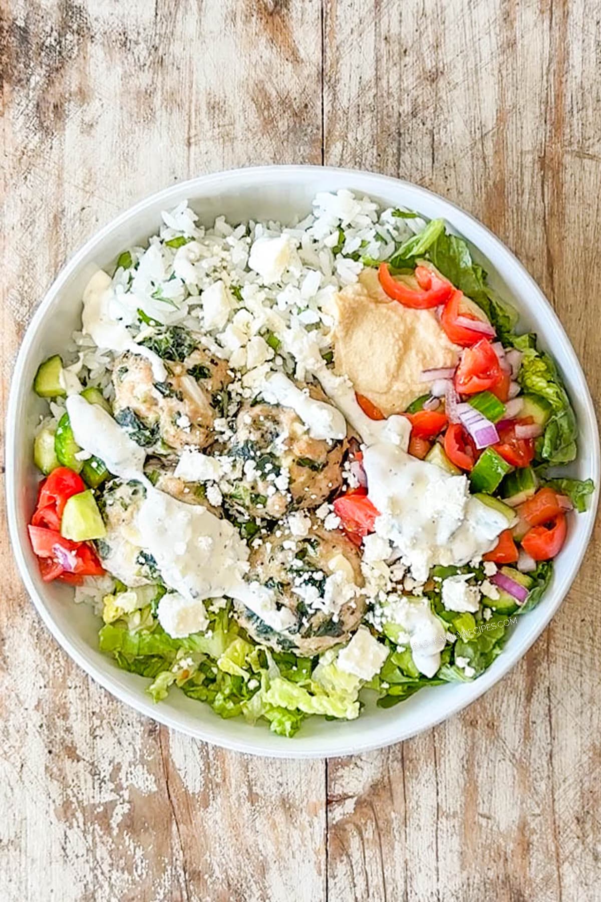 Meatballs topped with salad, tzatziki sauce and crumbled feta cheese.