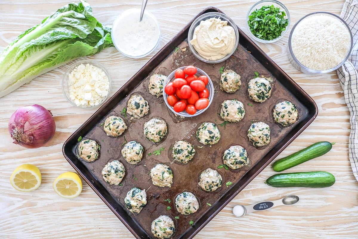 Ingredients needed to make Mediterranean meatball bowls on a wooden background.