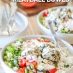 Side view of a Mediterranean meatball bowl with rice, salad, and sauce on a wooden background.