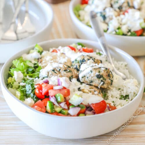 Close up of a Mediterranean meatball bowl with rice, veggies, meatballs and a drizzle of sauce.