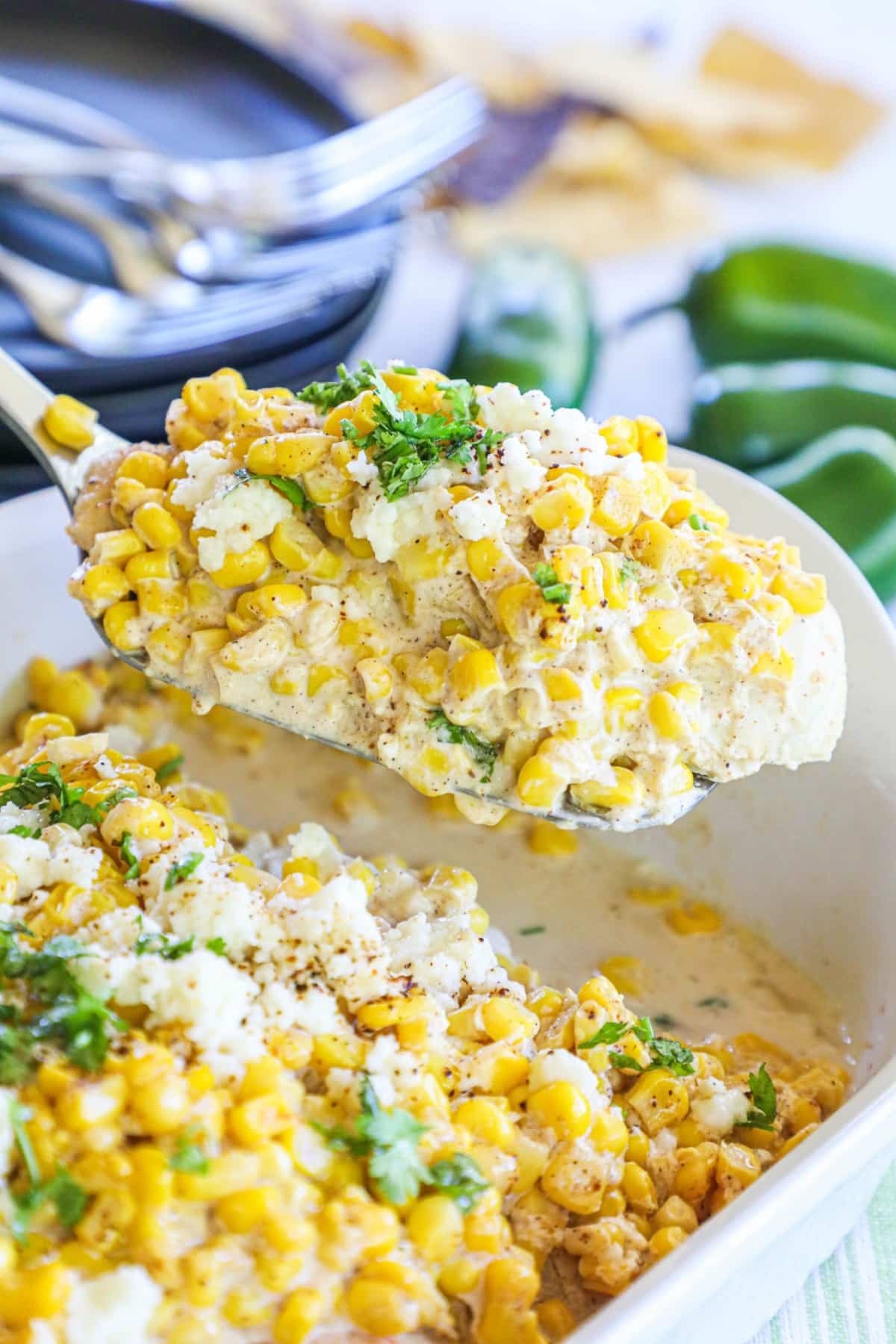 a spatula lifting a scoop of street corn chicken out of a white casserole dish