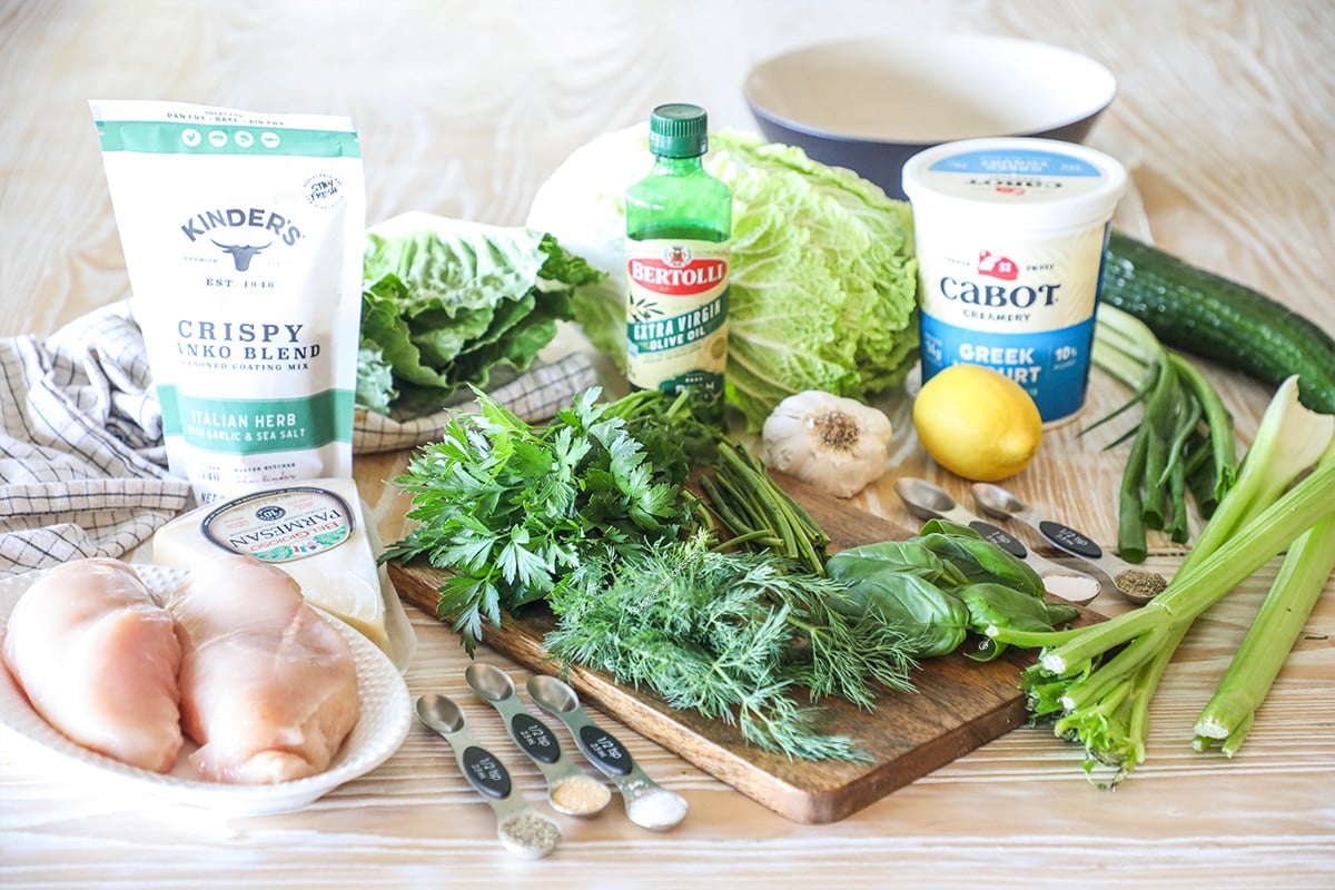 ingredients needed to make green parmesan chicken goddess salad- on a wooden board and wooden background