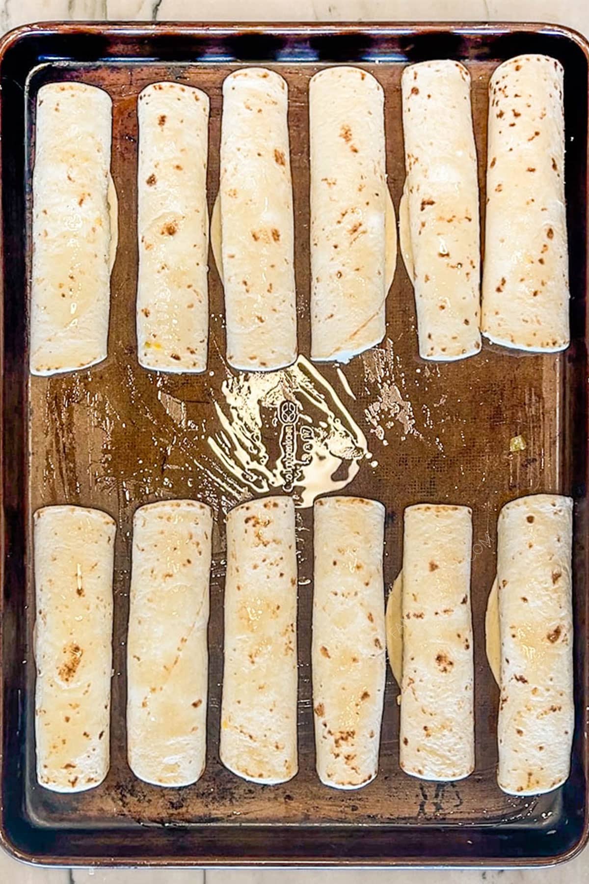 pan with uncooked, rolled tortillas for Baked Chicken Taquito recipe