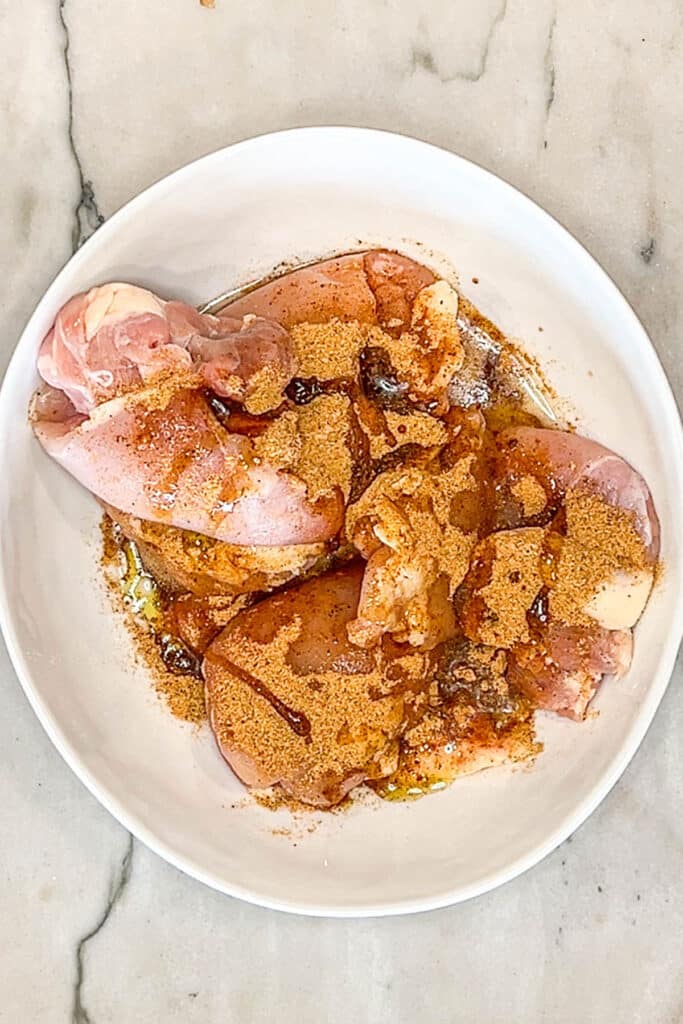 chicken filets in a bowl with spices.