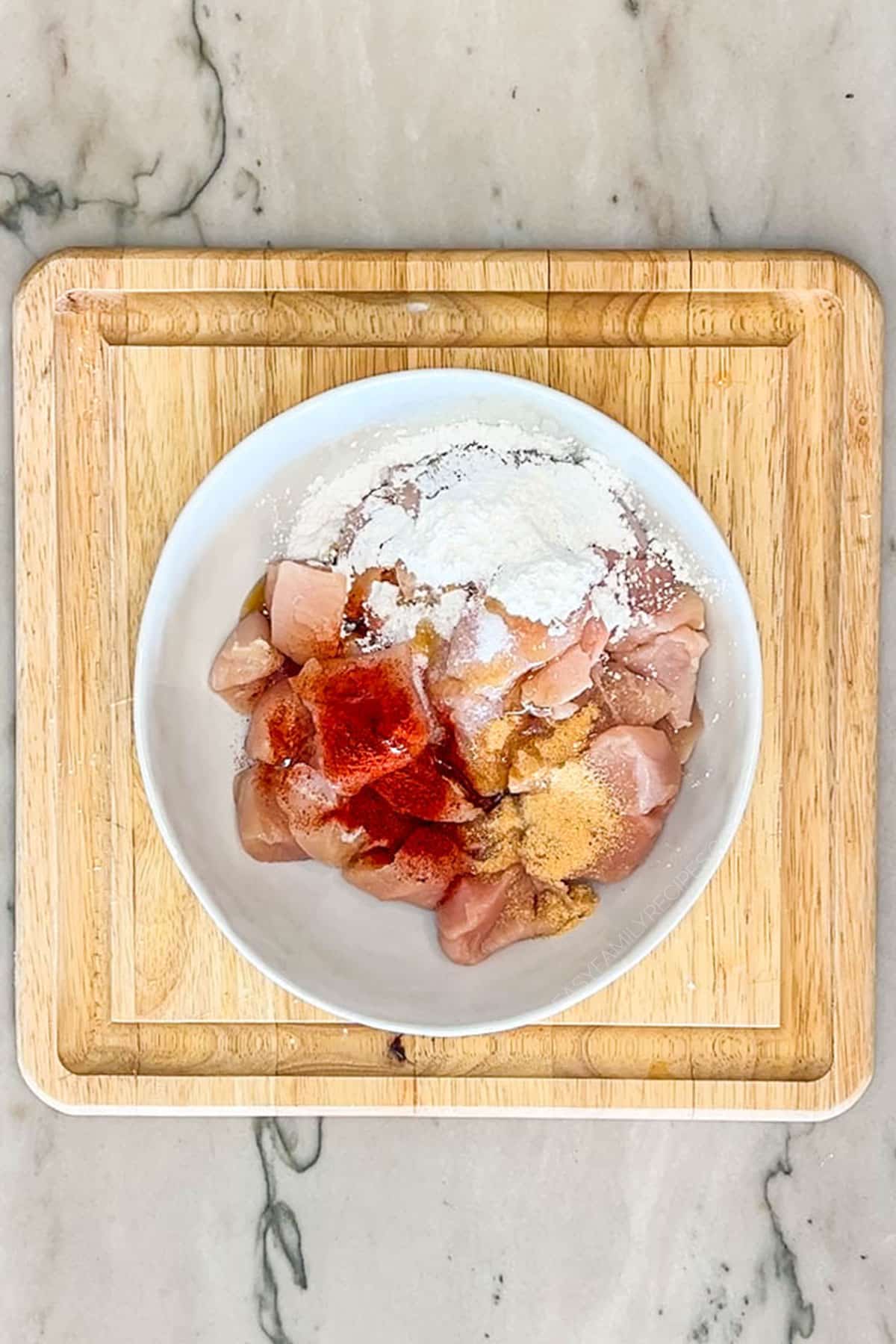 Chicken breast in pieces in a bowl with spices.