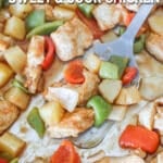 Overhead shot of sweet and sour chicken on a sheet pan with a spatula.