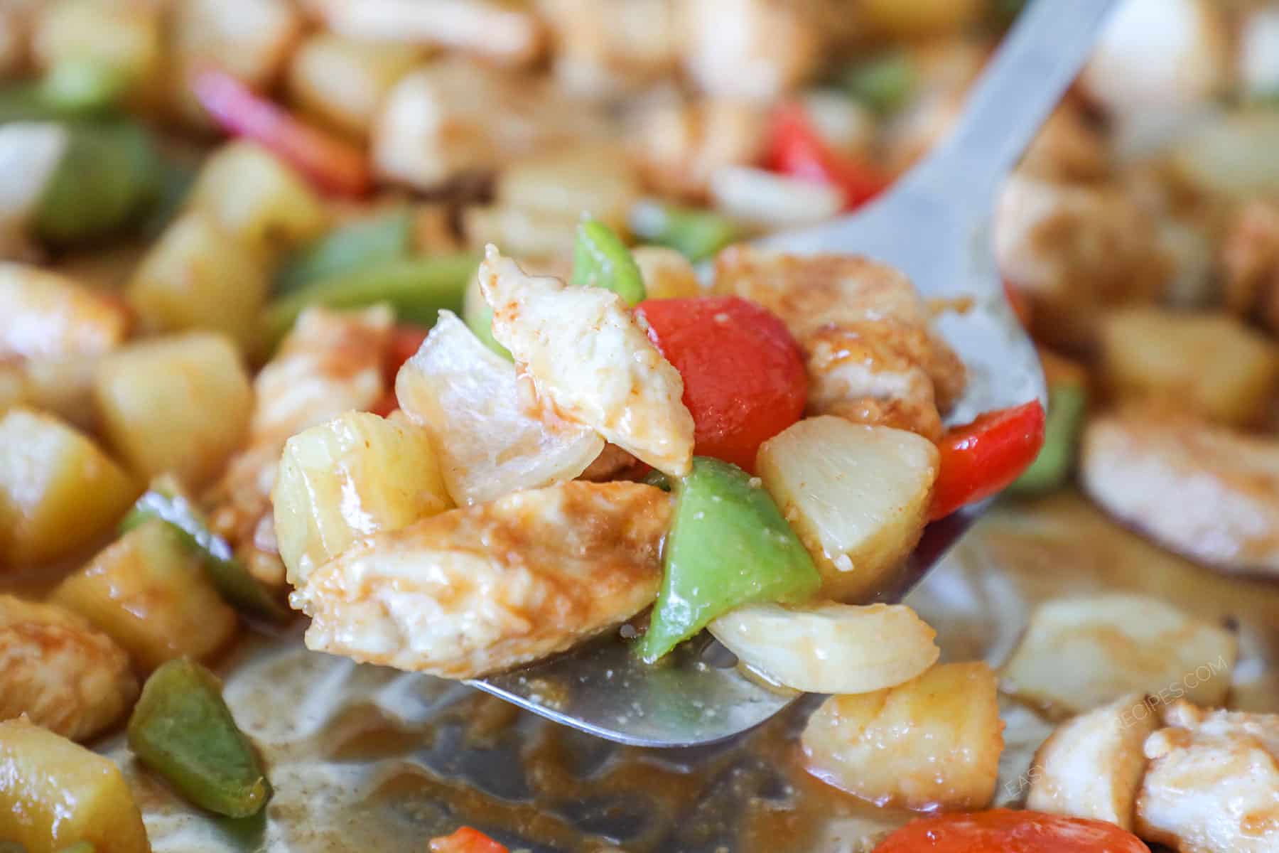 Sheet pan sweet and sour chicken scooped on a metal spatula.