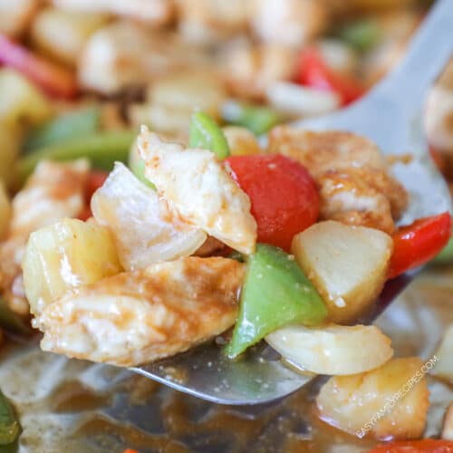 Metal spatula scooping up some sheet pan sweet and sour chicken.