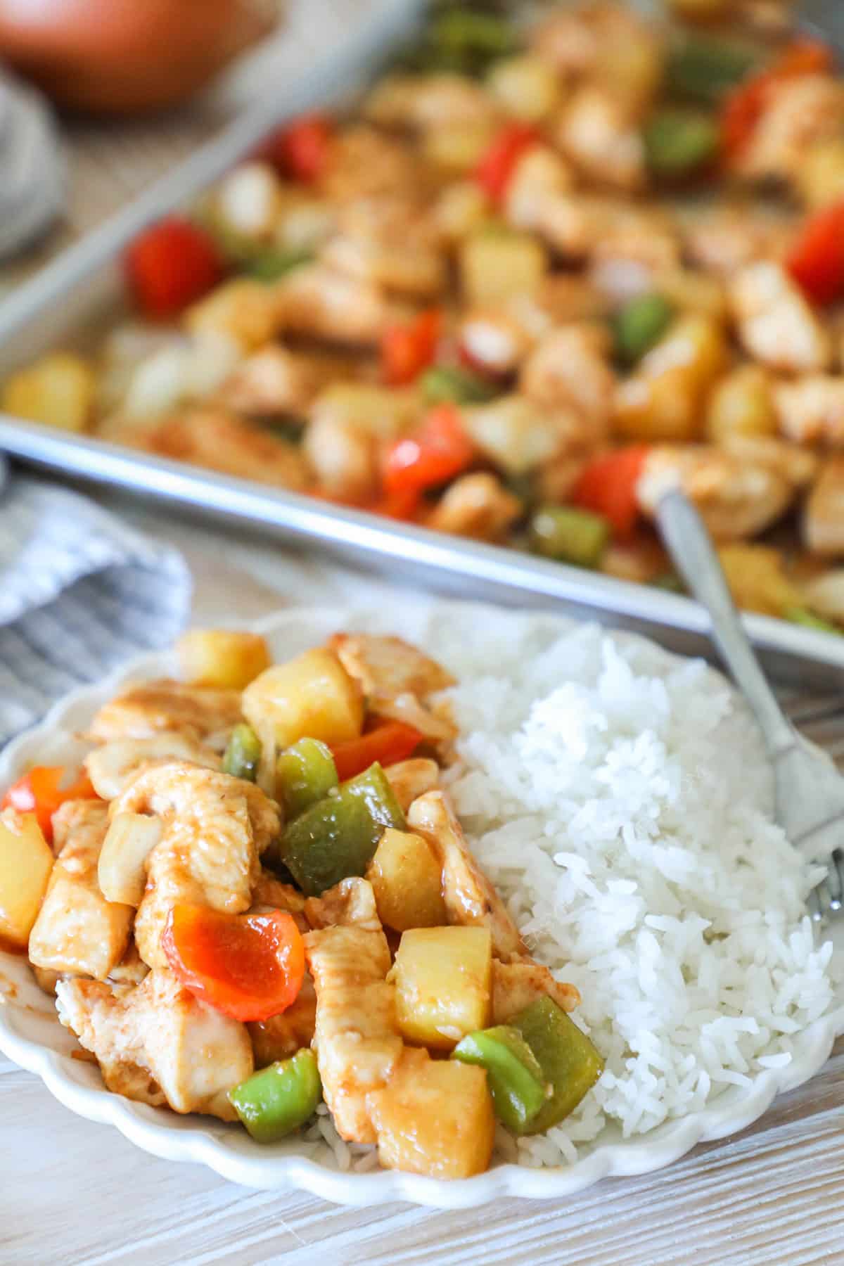Sweet and sour chicken served with white rice on a plate.