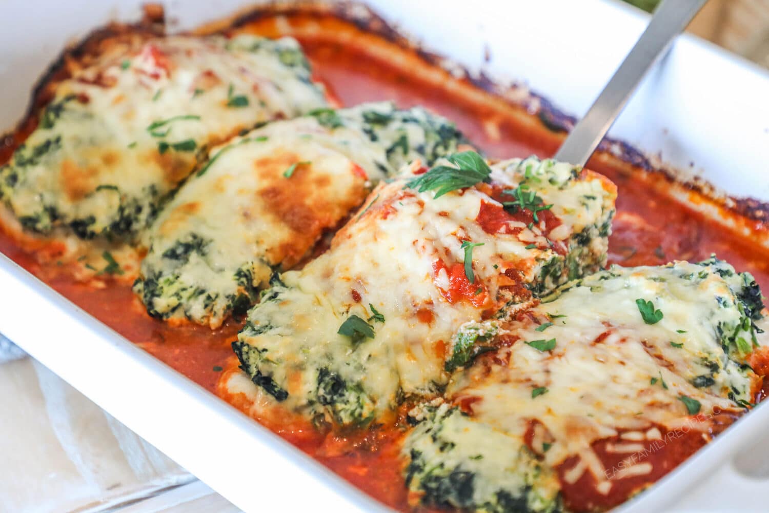 Close up of the spinach ricotta chicken bake in a white baking dish.