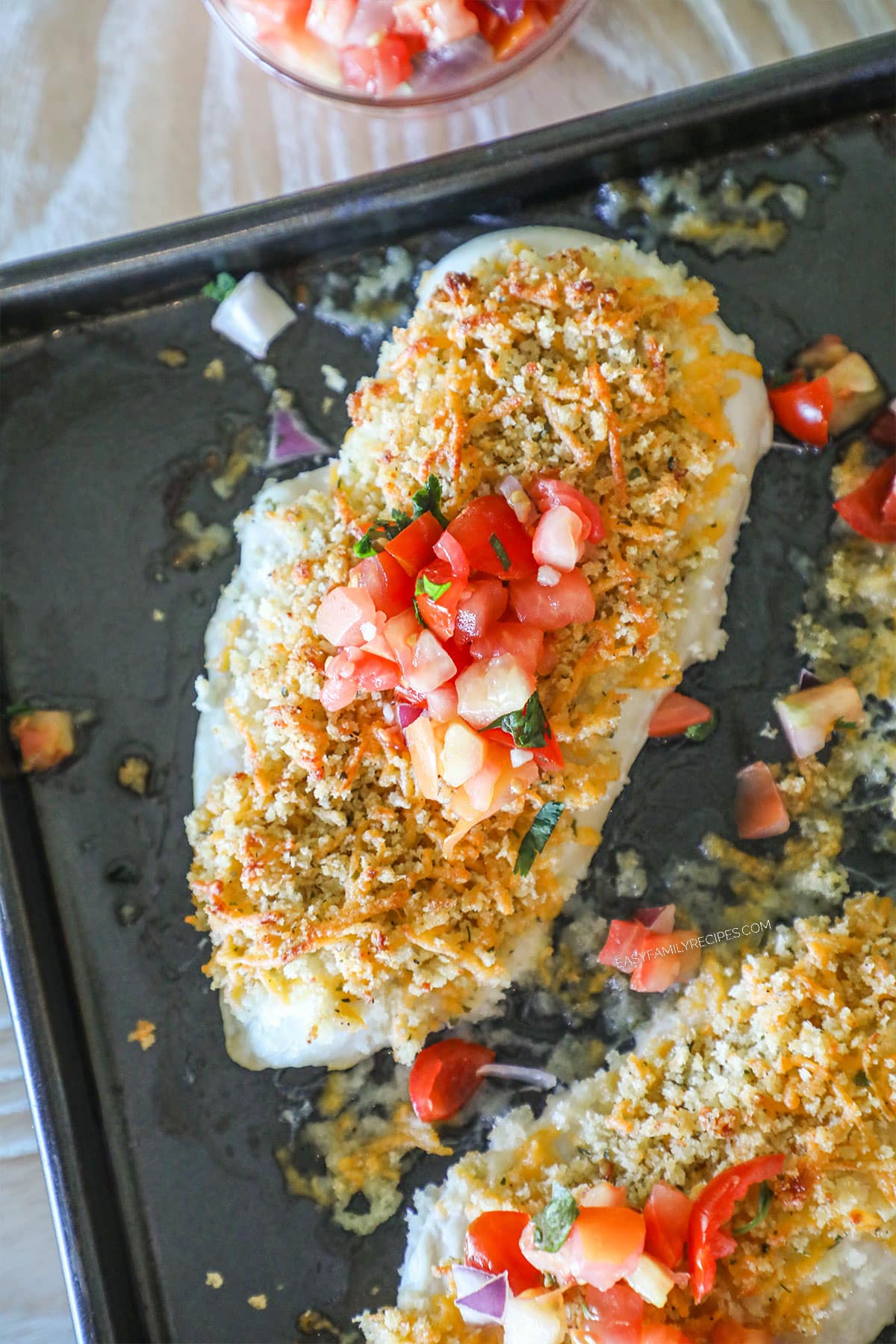 Overhead shot of panko cheddar chicken on a sheet pan with pico de gallo on top.