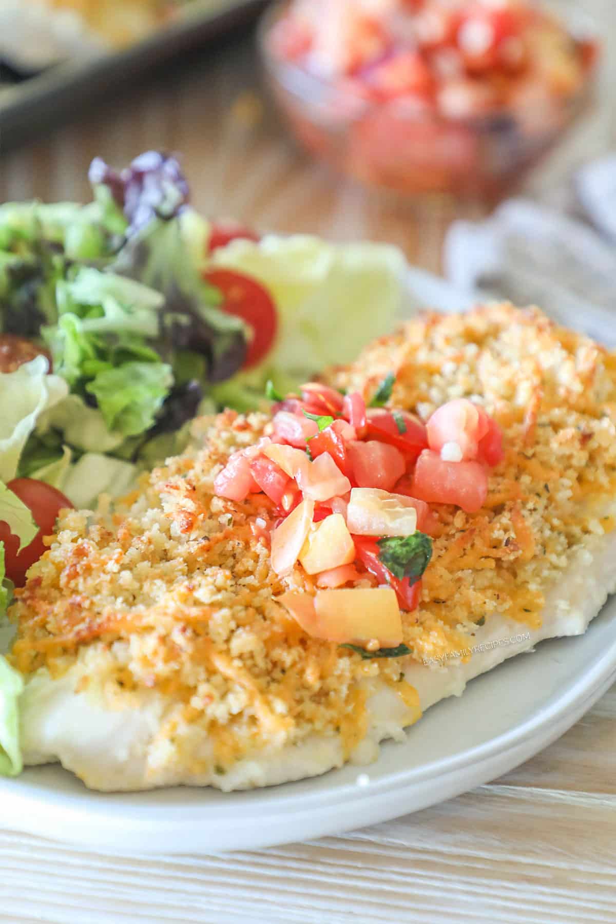 Side view of panko cheddar chicken on a plate topped with pico de gallo.
