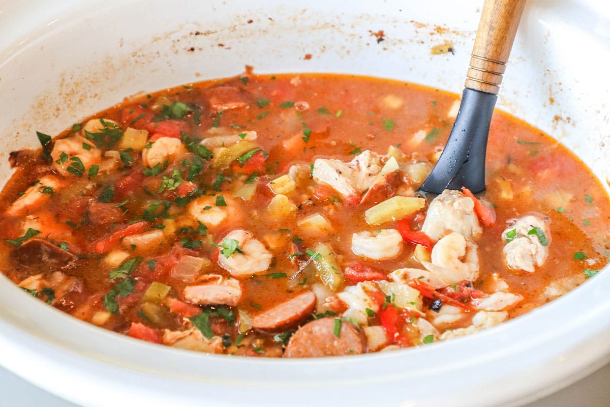 Slow cooker jambalaya in a white crock pot.