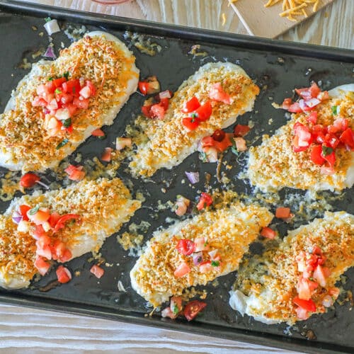 Overhead shot of six pieces of easy panko cheddar chicken on a sheet pan all topped with pico de gallo.