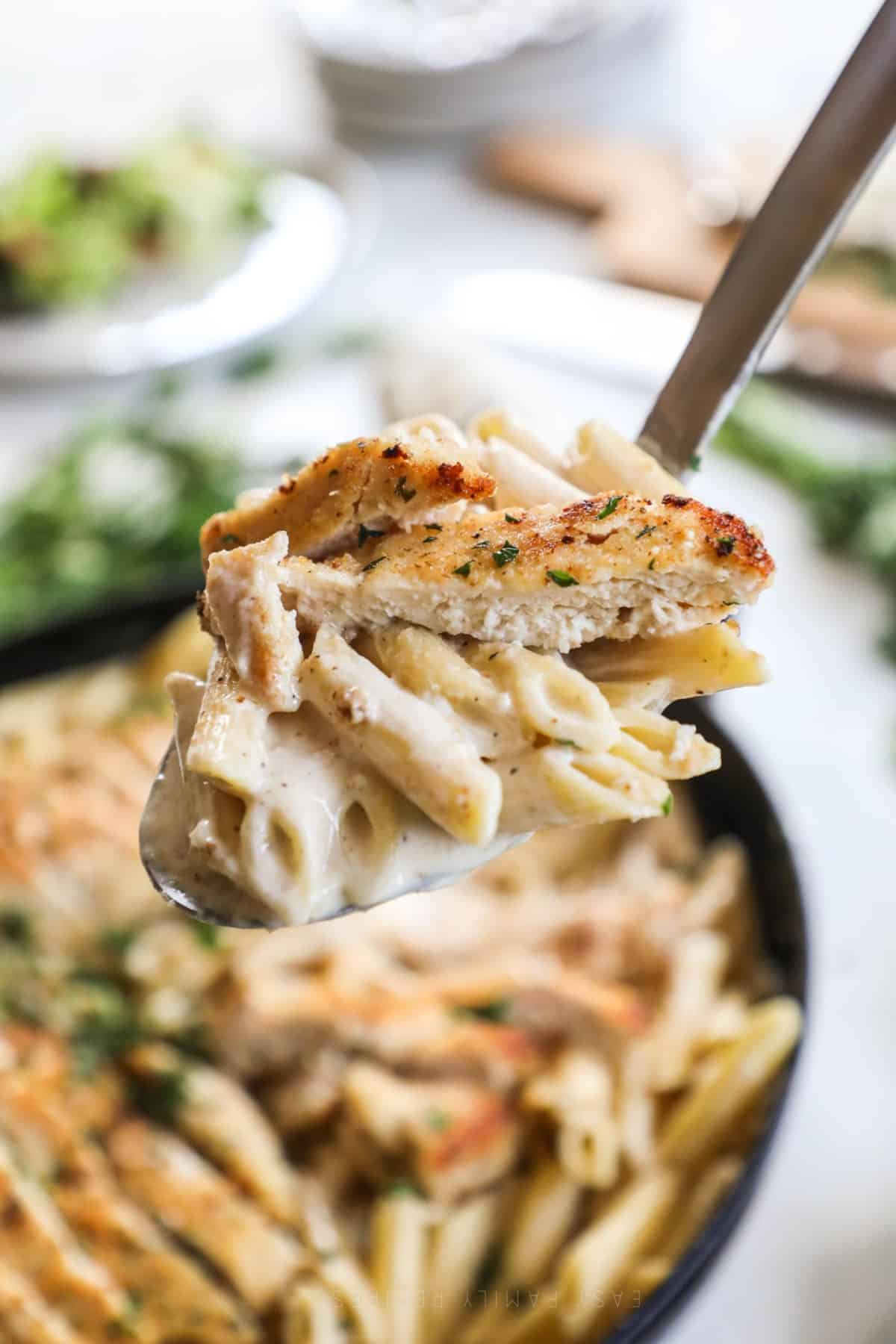 a scoop of garlic parmesan chicken pasta lifted from skillet