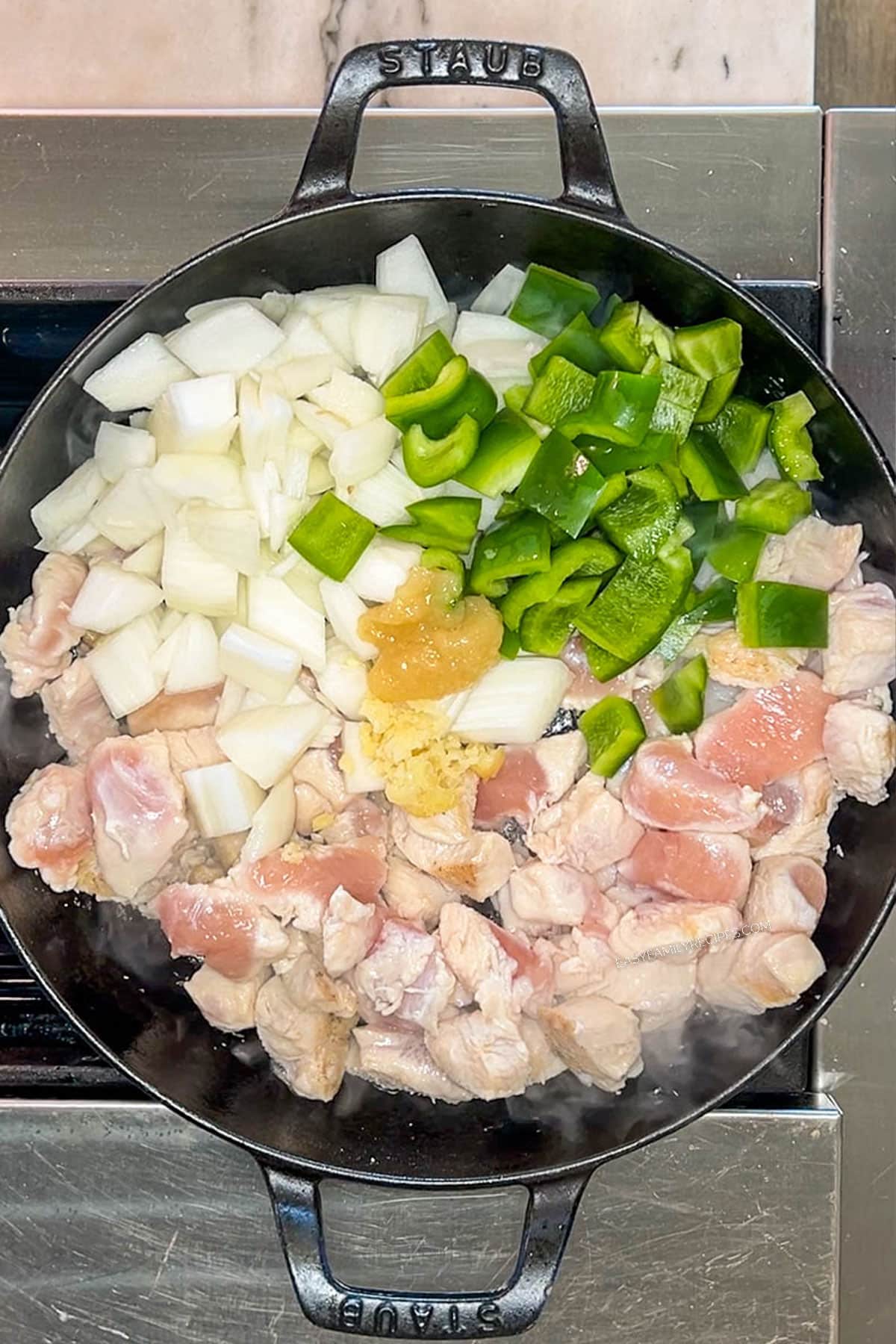 Diced chicken, bell peppers and onions in a skillet.