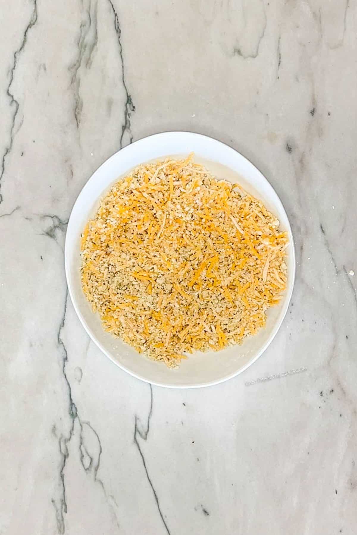 Panko breadcrumbs in a bowl with shredded cheddar cheese.
