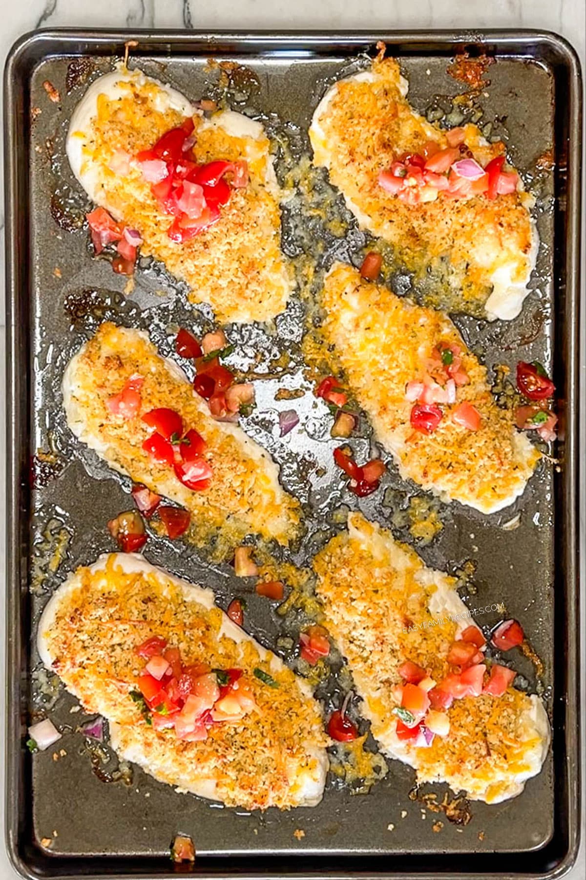 Finished panko cheddar chicken on a sheet pan with pico de gallo on top.