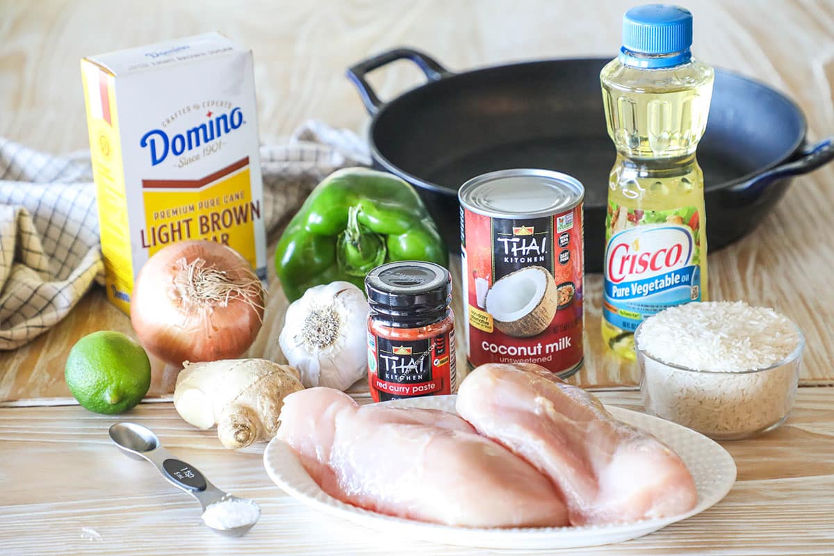 Ingredients needed to make one pan chicken curry on a wooden background.