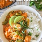 Overhead shot of chicken curry served with rice, garnished with lime wedges.