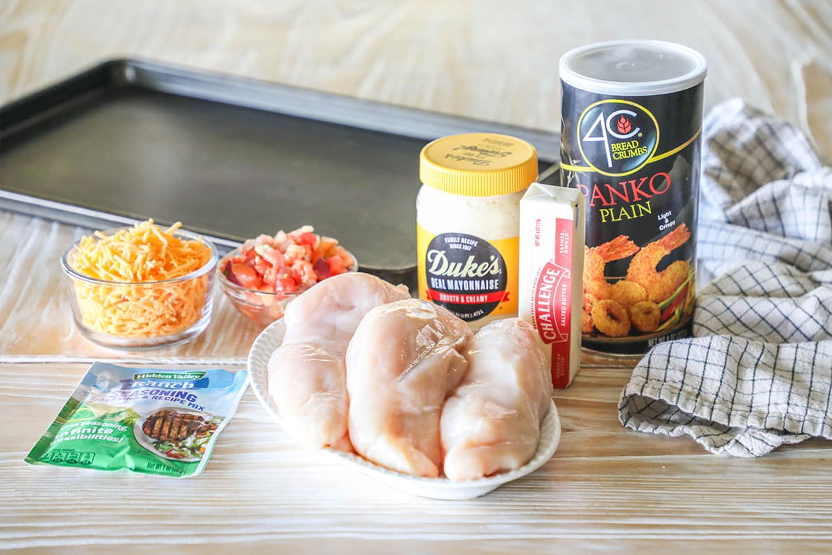 Ingredients needed to make panko cheddar chicken on a wooden background.