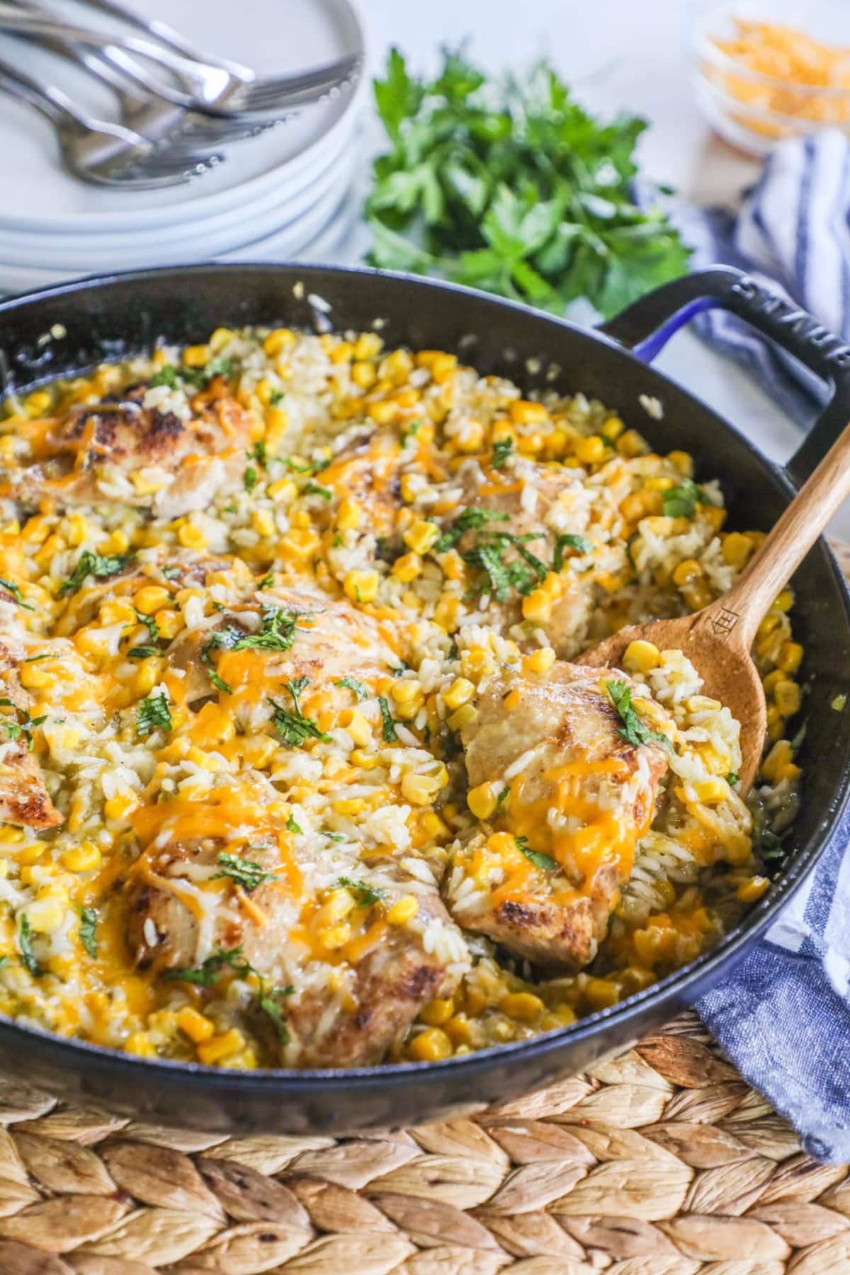 salsa verde chicken and rice in a cast iron skillet with a wooden spoon to one side
