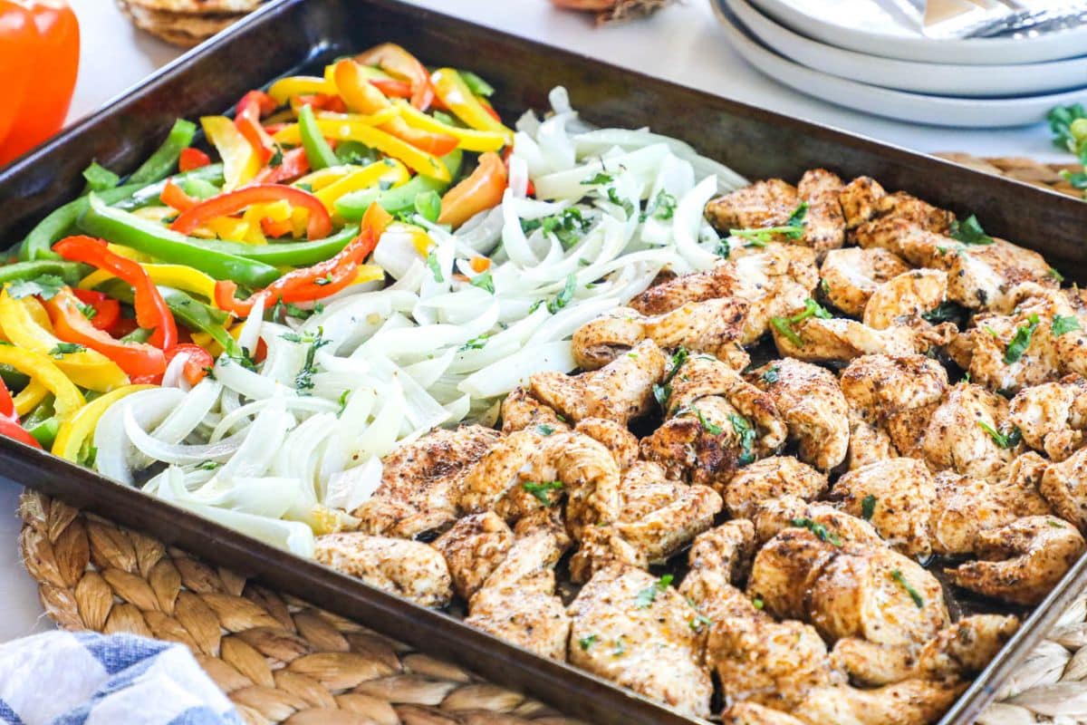 a sheet pan with grilled chicken, onions, and a mix of colored peppers for fajitas