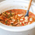 White crockpot with slow cooker jamabalaya- with wooden spoon in pot