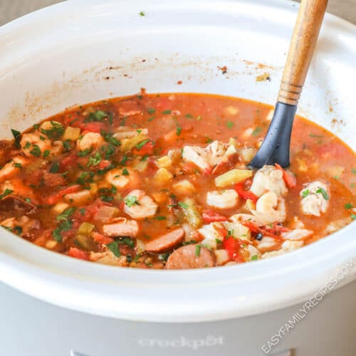 White crockpot with slow cooker jamabalaya- with wooden spoon in pot