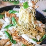 Brown butter spaghetti with chicken, basil and burrata in pan with pasta being lifted out. On a wooden background.