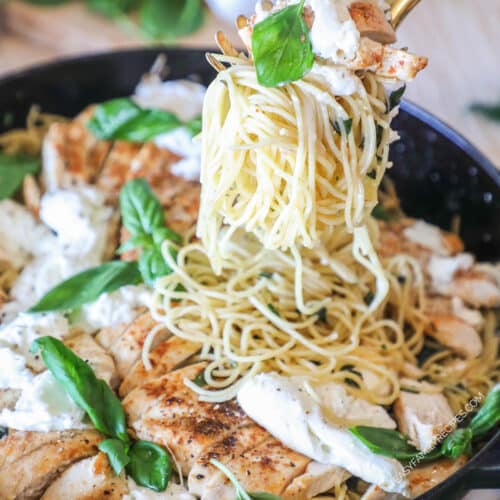 Brown butter spaghetti with chicken, basil and burrata in pan with pasta being lifted out
